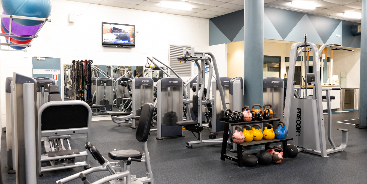 A photo of a busy section of the gym filled with machines and active equipment