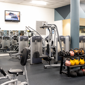 A photo of a busy section of the gym filled with machines and active equipment