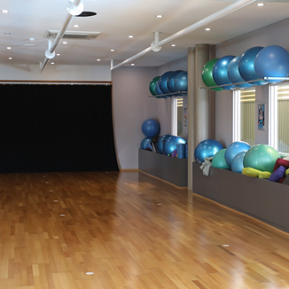 A photo of an empty wooden floor room with exercise and balance balls stored on the right side