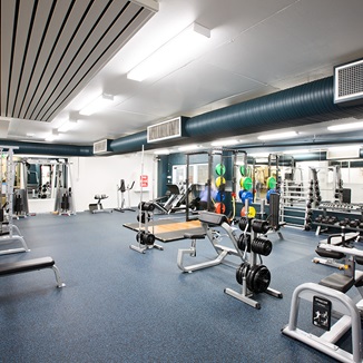 A photo of an active area with free weights and benches spread around