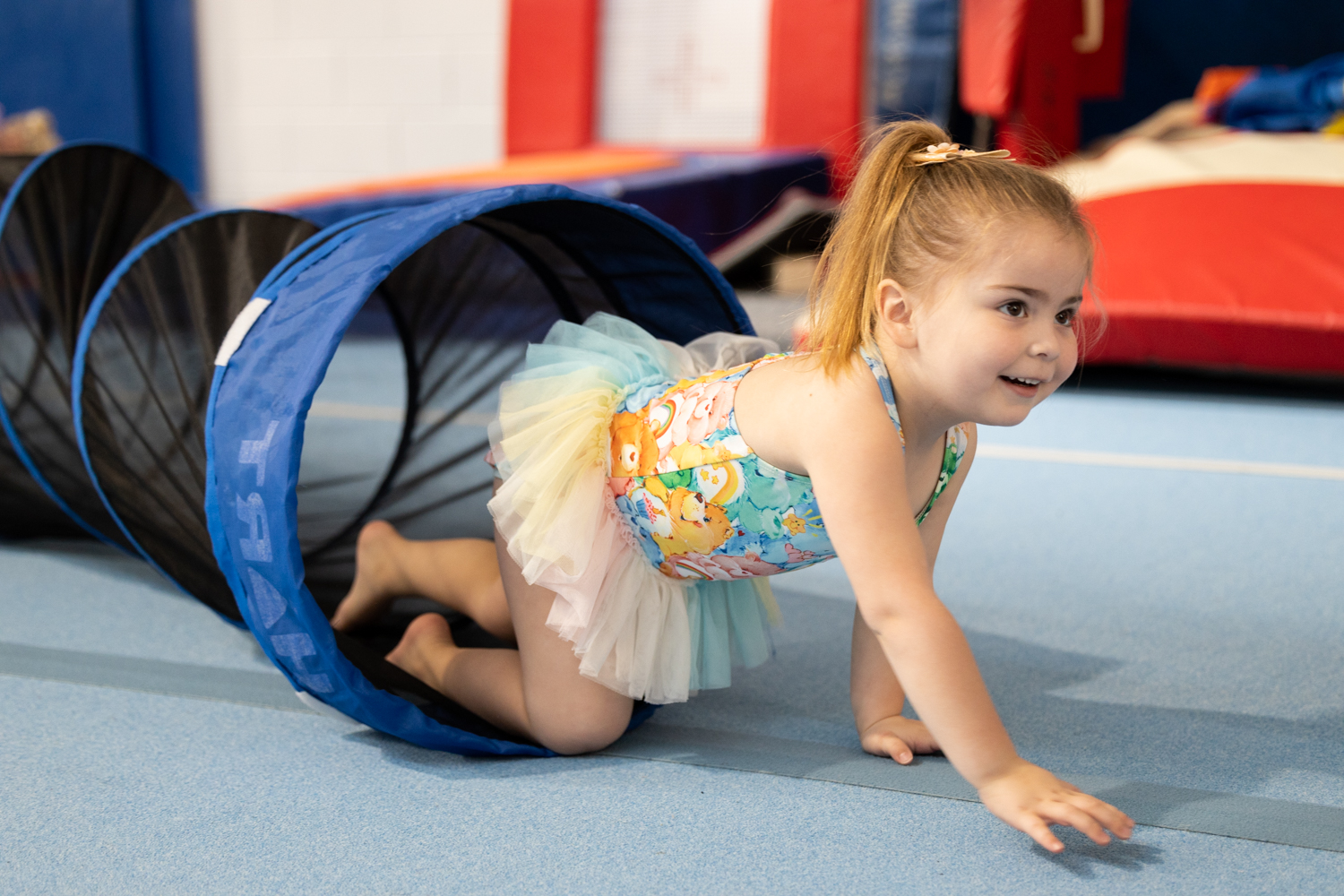 Young girl crawling through play tunnel at kids gymnastics