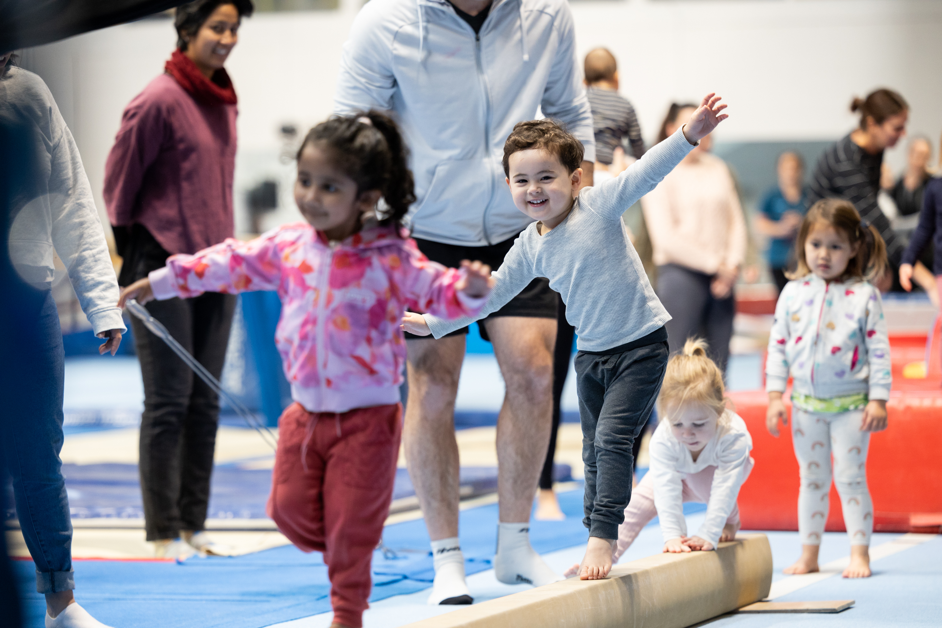 A group of kids balancing as they walk along a bar on the floor at the HBF Stadium Kids Gymnastics in Mount Claremont, Perth