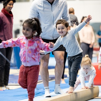 A group of kids balancing as they walk along a bar on the floor at the HBF Stadium Kids Gymnastics in Mount Claremont, Perth