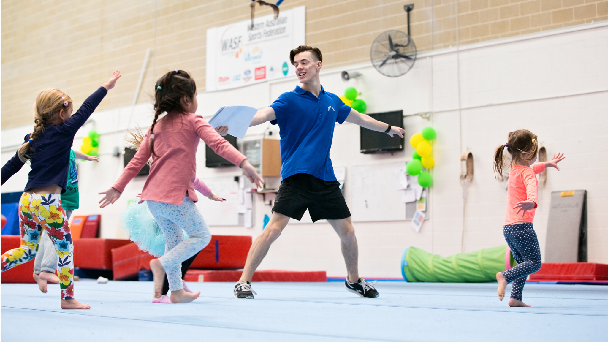 A group of kids being led in a stretching routine by an instructor at the HBF Stadium Kids Gymnastics in Mount Claremont, Perth