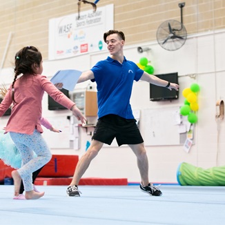 A group of kids being led in a stretching routine by an instructor at the HBF Stadium Kids Gymnastics in Mount Claremont, Perth
